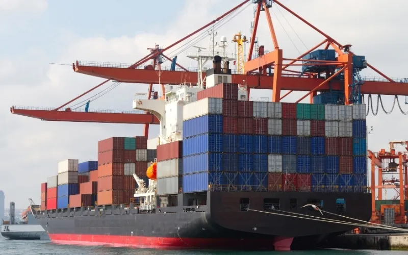 Großes Containerschiff im Hafen mit Kränen beim Be- und Entladen, Symbol für internationalen Handel und globale Logistik.